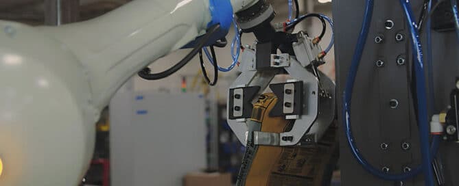 Robotic arm performing automated valve bag placement in a manufacturing facility.