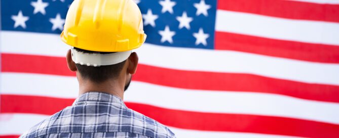 Man with hardhat in front of American flag to symbolize Production Reshoring