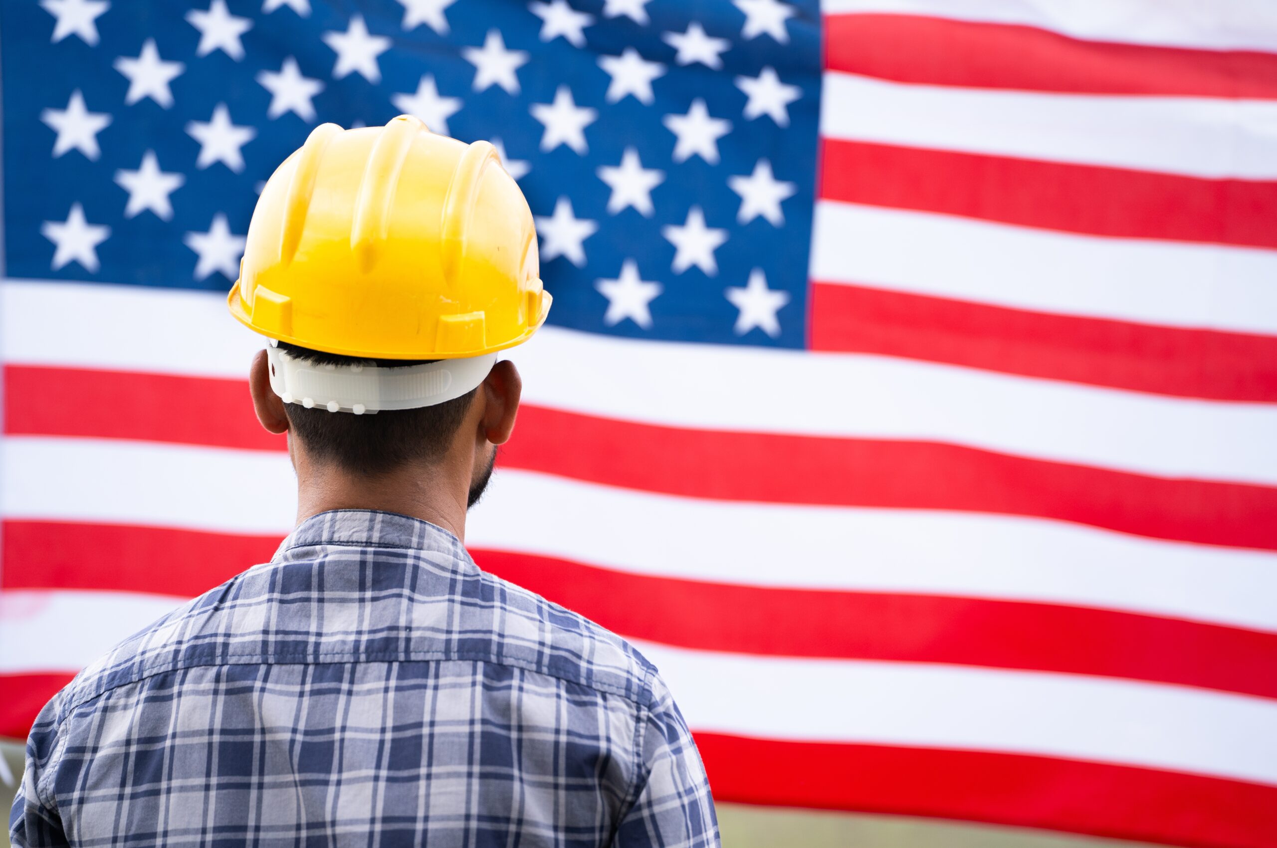 Man with hardhat in front of american flag to symbolize production reshoring