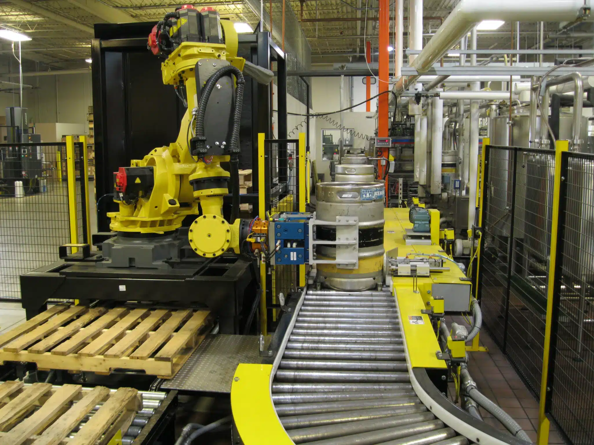 PASCO automated robotic arm palletizing metal beer kegs on a production conveyor system.