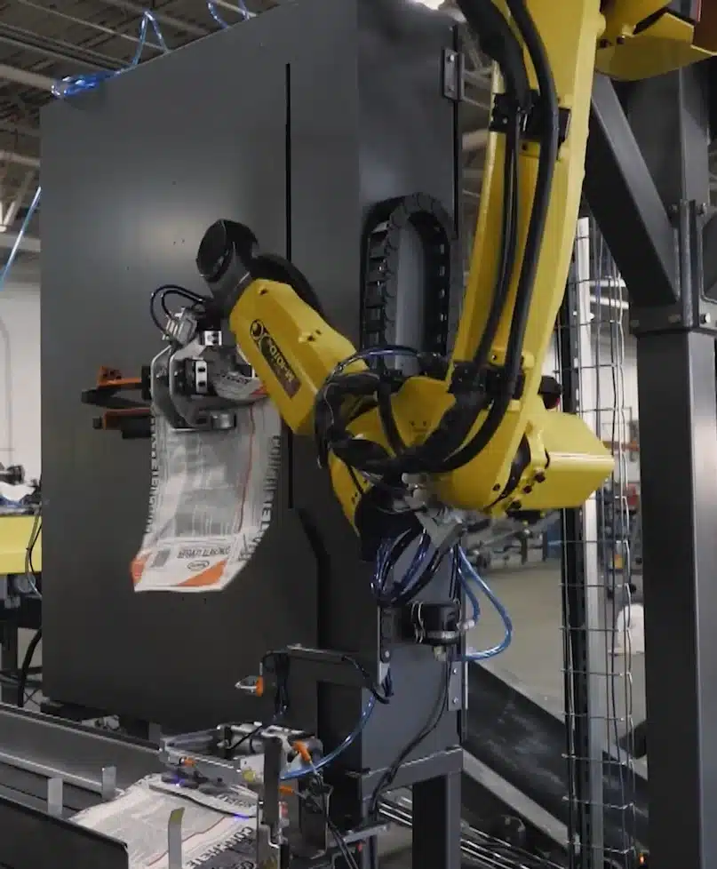 PASCO robotic valve bag placer positioning a cement bag on an automated packaging line.